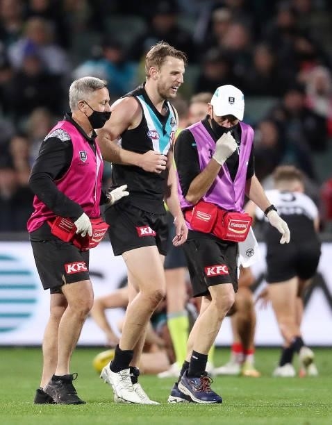 Trent McKenzie of the Power in the hands of trainers after hurting a shoulder during the 2021 AFL Round 15 match between the Port Adelaide Power and...