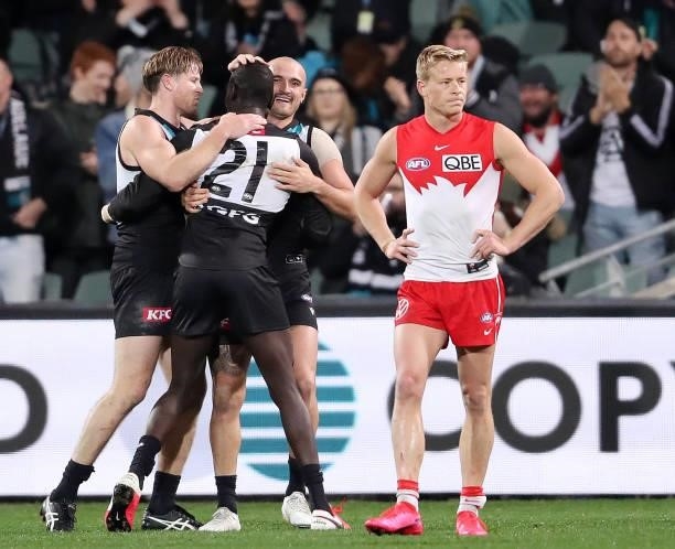 Isaac Heeney of the Swans walks away from Port players celebrating the win, including Tom Jonas, Sam Powell-Pepper, Aliir Aliir during the 2021 AFL...