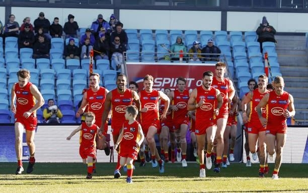 The Gold Coast Suns run on to the field before the 2021 AFL Round 15 match between the North Melbourne Kangaroos and the Gold Coast Suns at...