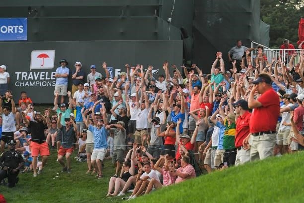 Fans do the wave around the 18th green during the eighth playoff hole during the final round of the Travelers Championship at TPC River Highlands on...