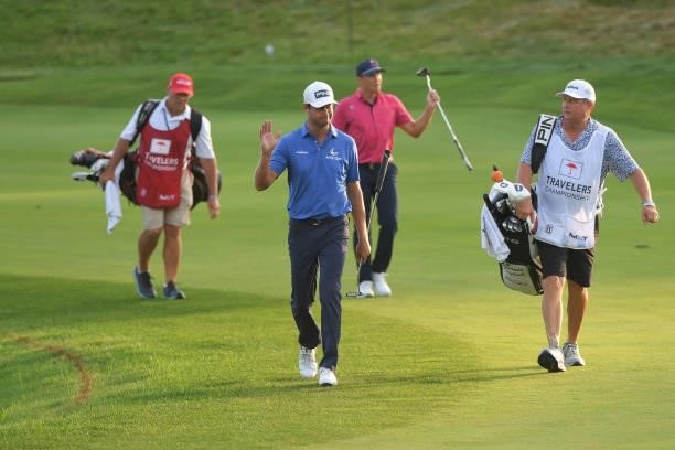 Harris English and Kramer Hickok wave to fans while walking towards the 17th green during the fifth playoff hole during the final round of the...