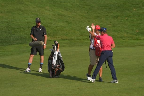Kramer Hickok high fives his caddie after hitting a close shot on the 18th green during the final round of the Travelers Championship at TPC River...
