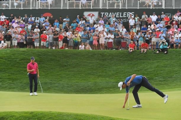 Harris English and Kramer Hickok play the 18th green during the seventh playoff hole during the final round of the Travelers Championship at TPC...