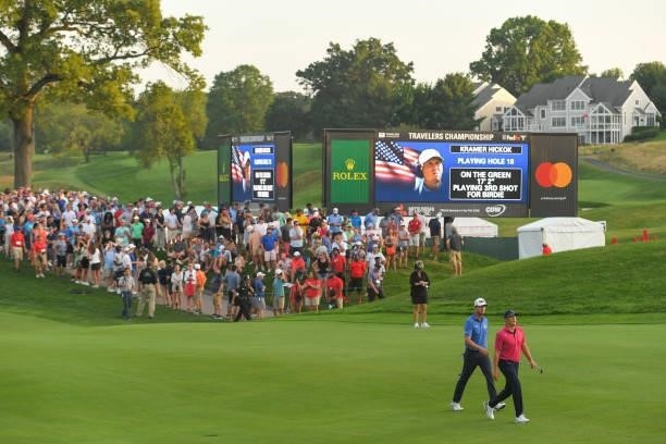 Harris English and Kramer Hickok walk along the 18th fairway during the seventh playoff hole during the final round of the Travelers Championship at...