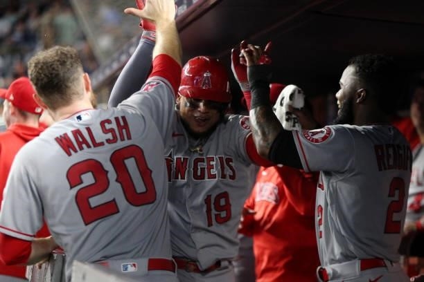 Juan Lagares of the Los Angeles Angels celebrates with teammates Jared Walsh and Luis Rengifo in the dugout after hitting a home run during the game...