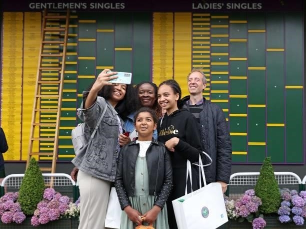 People pose for a photograph in front of the progress board on the second day of the 2021 Wimbledon Championships at The All England Tennis Club in...