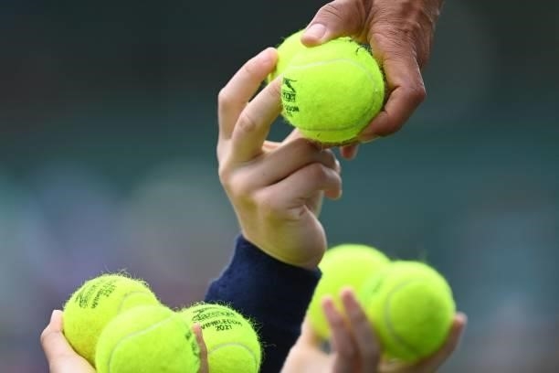 Balls are passed to an umpire on the second day of the 2021 Wimbledon Championships at The All England Tennis Club in Wimbledon, southwest London, on...