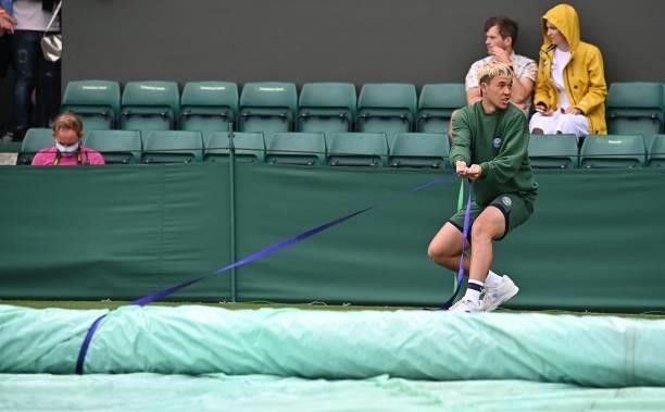 Ground staff pull rain covers on Court 4 during the second day of the 2021 Wimbledon Championships at The All England Tennis Club in Wimbledon,...