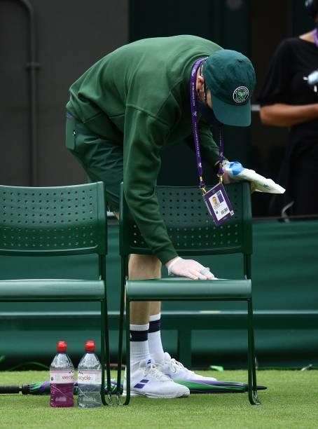 Member of the ground staff sanitizes player's chairs after the men's singles first round match between Spain's Feliciano Lopez and Britain's Daniel...