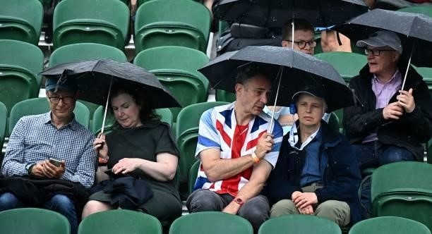 Spectators take cover from the rain on Court 2 during the second day of the 2021 Wimbledon Championships at The All England Tennis Club in Wimbledon,...