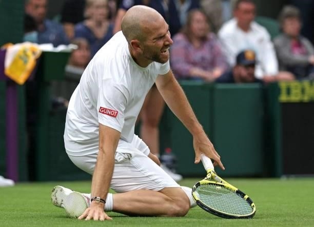 France's Adrian Mannarino reacts as he slips on the grass during play against Switzerland's Roger Federer during their men's singles first round...
