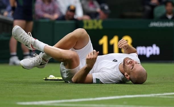 France's Adrian Mannarino reacts after slipping on the grass during play against Switzerland's Roger Federer during their men's singles first round...