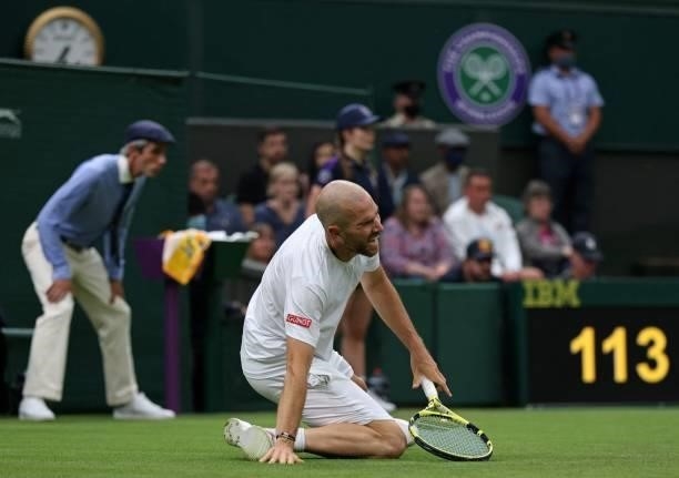France's Adrian Mannarino reacts as he slips on the grass during play against Switzerland's Roger Federer during their men's singles first round...