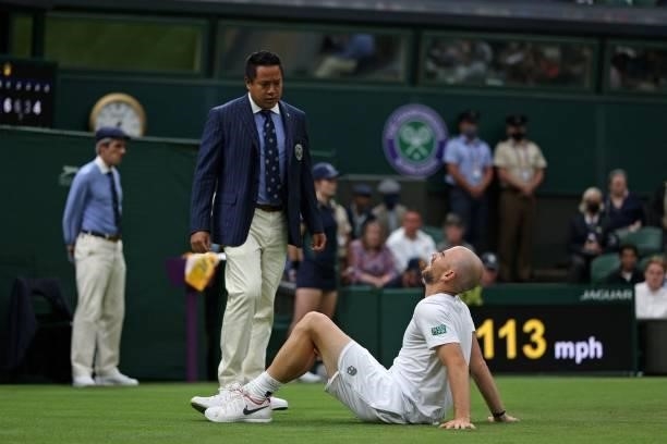 France's Adrian Mannarino speaks to the Umpire after slipping on the grass while playing against Switzerland's Roger Federer during their men's...