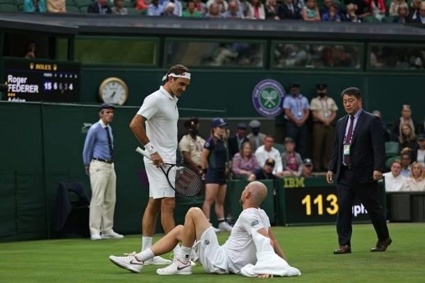 Switzerland's Roger Federer talks to France's Adrian Mannarino after Mannarino slipped on the grass during their men's singles first round match on...