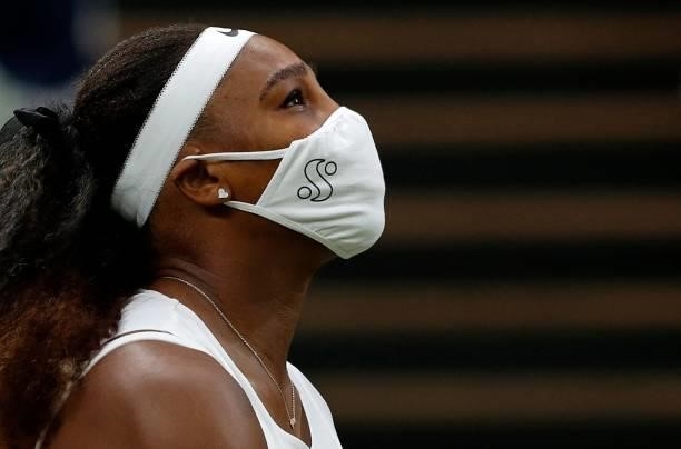 Player Serena Williams, wearing a face covering to combat the spread of coronavirus, arrives back on court after leaving for treatment, during her...