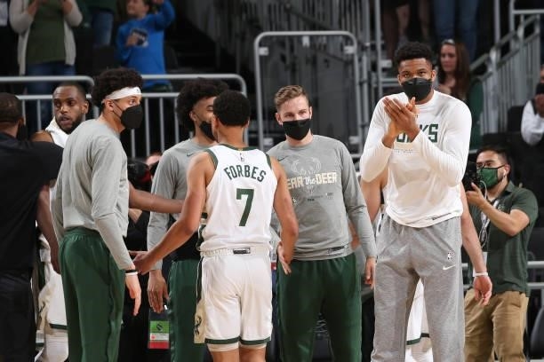 Giannis Antetokounmpo hi-fives Bryn Forbes and Elijah Bryant of the Milwaukee Bucks during Game 5 of the Eastern Conference Finals of the 2021 NBA...