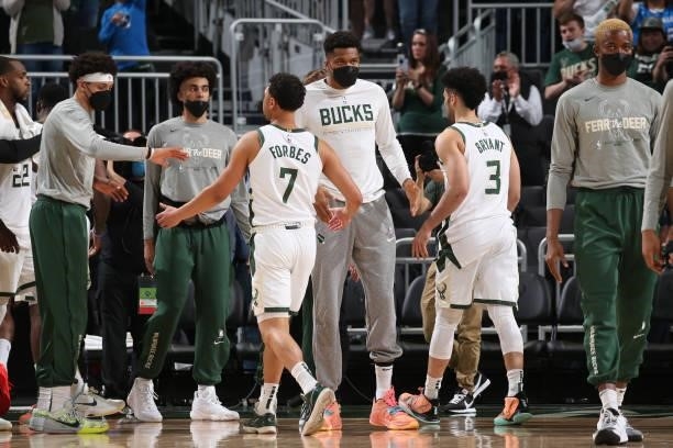 Giannis Antetokounmpo hi-fives Bryn Forbes and Elijah Bryant of the Milwaukee Bucks during Game 5 of the Eastern Conference Finals of the 2021 NBA...