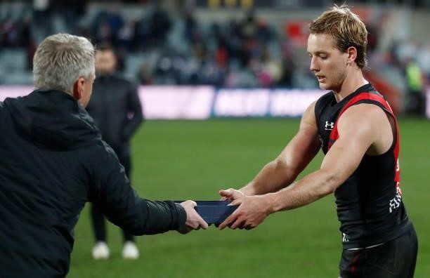 Darcy Parish of the Bombers is presented the Tom Wills Medal during the 2021 AFL Round 16 match between the Geelong Cats and the Essendon Bombers at...
