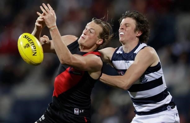 Mason Redman of the Bombers and Max Holmes of the Cats compete for the ball during the 2021 AFL Round 16 match between the Geelong Cats and the...
