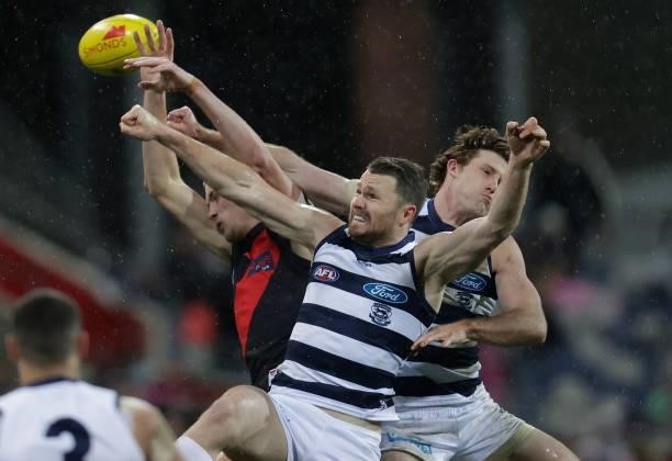 Nikolas Cox of the Bombers, Patrick Dangerfield of the Cats and Jed Bews of the Cats compete for the ball during the 2021 AFL Round 16 match between...