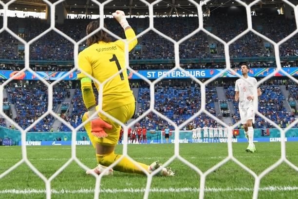Switzerland's goalkeeper Yann Sommer celoebrates as Spain's midfielder Sergio Busquets reacts after hitting the goal post during a penalty shoot-out...