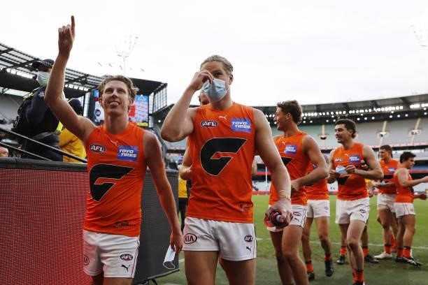 Lachie Whitfield and Harry Himmelberg of the Giants leave the field after a win during the 2021 AFL Round 16 match between the Melbourne Demons and...