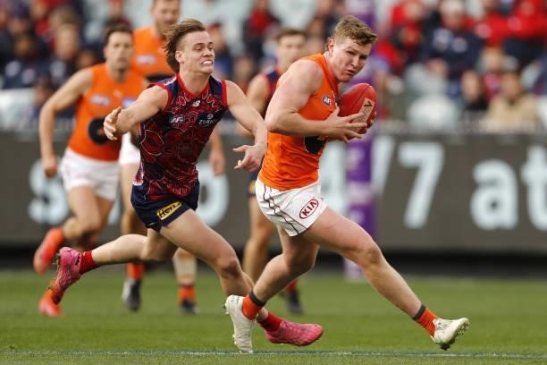 Tom Green of the Giants runs the ball against Trent Rivers of the Demons during the 2021 AFL Round 16 match between the Melbourne Demons and the GWS...