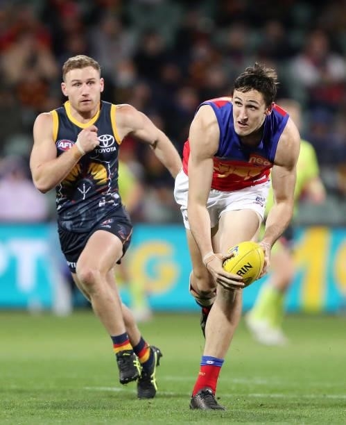 Oscar McInerney of the Lions handpasses the ball against Rory Laird of the Crows during the 2021 AFL Round 16 match between the Adelaide Crows and...
