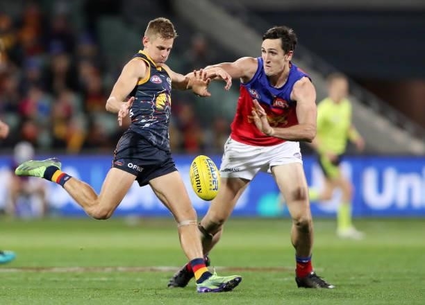 David Mackay of the Crows kicks the ball against Oscar McInerney of the Lions during the 2021 AFL Round 16 match between the Adelaide Crows and the...