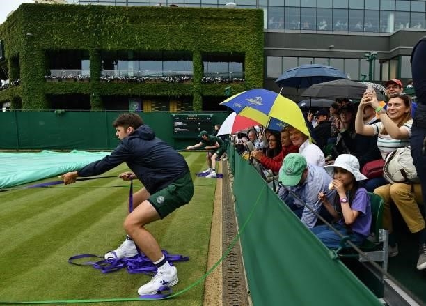 Spectators shelter from the rain beneath umbrellas on the sixth day of the 2021 Wimbledon Championships at The All England Tennis Club in Wimbledon,...