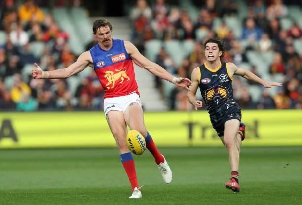 Joe Daniher of the Lions kicks the ball with the running Ned McHenry of the Crows during the 2021 AFL Round 16 match between the Adelaide Crows and...