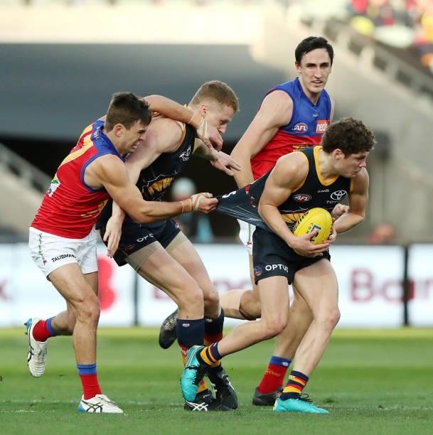 Harry Schoenberg of the Crows tries to get free from Jarryd Lyons of the Lions with Reilly O'Brien of the Crows and Oscar McInerneyduring the 2021...