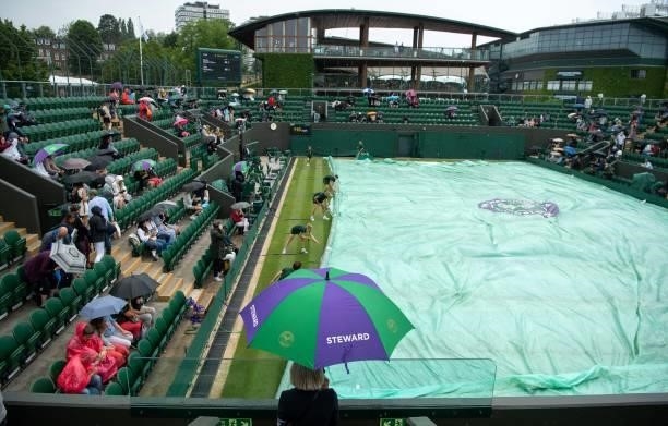 Ground staff pull on the court covers as rain stops play on court 3 on the sixth day of the 2021 Wimbledon Championships at The All England Tennis...