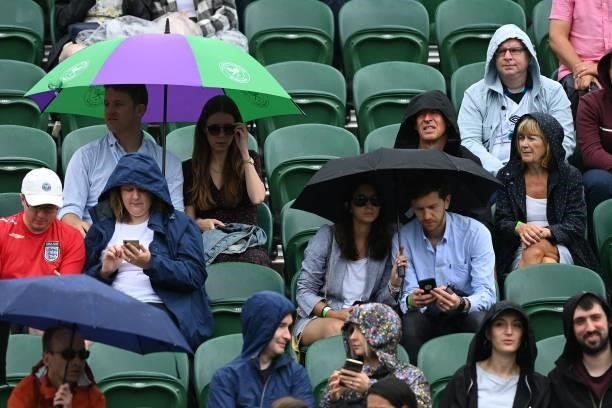 Spectators huddle under umbrellas as they watch Belarus' Aliaksandra Sasnovich play Germany's Angelique Kerber during their women's singles third...