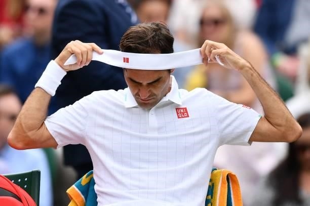 Switzerland's Roger Federer changes his head band during a break in play against Britain's Cameron Norrie at their men's singles third round match on...