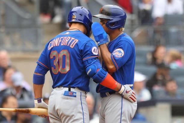 Francisco Lindor of the New York Mets whispers to Michael Conforto after scoring on a single by James McCann during the fifth inning of a game...