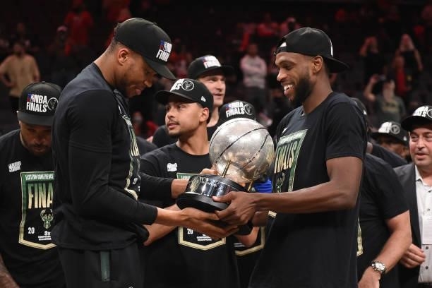 Khris Middleton of the Milwaukee Bucks hands the Eastern Conference Finals Trophy to teammates Giannis Antetokounmpo after the game against the...