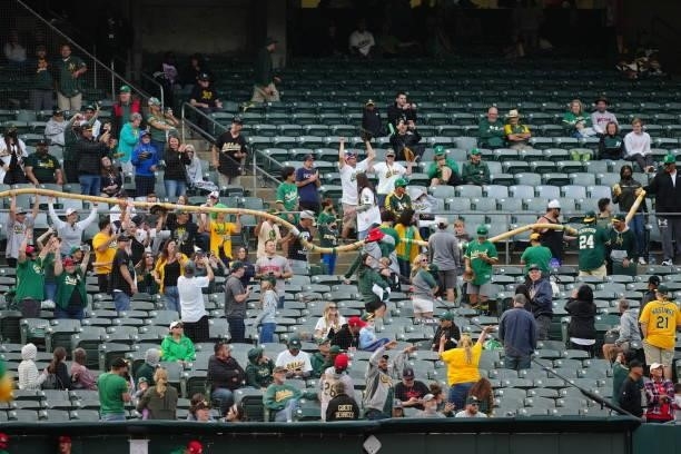 Fans string together drinking cups during the game between the Boston Red Sox and the Oakland Athletics at Oakland Coliseum on Saturday, July 3, 2021...