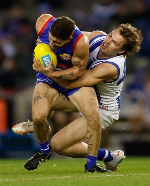 Tom Liberatore of the Bulldogs is tackled by Cameron Zurhaar of the Kangaroos during the 2021 AFL Round 16 match between the Western Bulldogs and the...