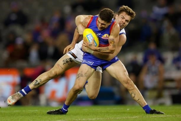 Tom Liberatore of the Bulldogs is tackled by Cameron Zurhaar of the Kangaroos during the 2021 AFL Round 16 match between the Western Bulldogs and the...