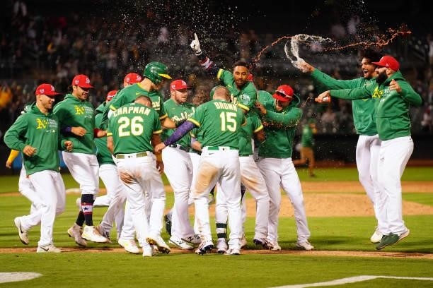 Tony Kemp of the Oakland Athletics celebrates with teammates after hitting a sacrifice fly as the Athletics defeat the Boston Red Sox 7-6 in twelve...