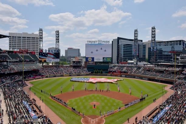 The Atlanta Braves honor America with a giant flag display, members of the Sons of the American Revolution in period dress, and a military flyover at...