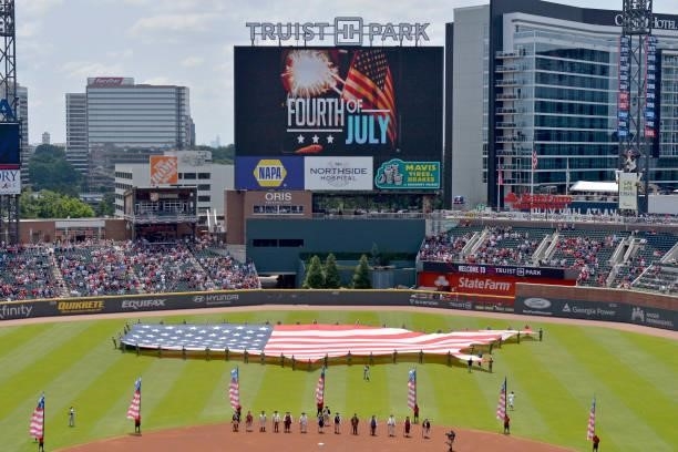 The Atlanta Braves honor America with a giant flag display and members of the Sons of the American Revolution in period dress at Truist Park on July...