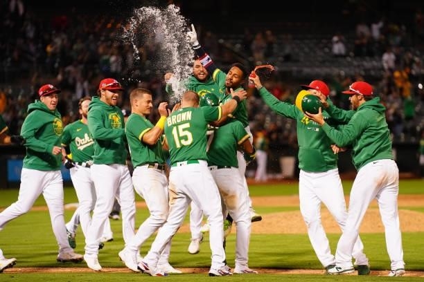 Tony Kemp of the Oakland Athletics celebrates with teammates after hitting a sacrifice fly as the Athletics defeat the Boston Red Sox 7-6 in twelve...