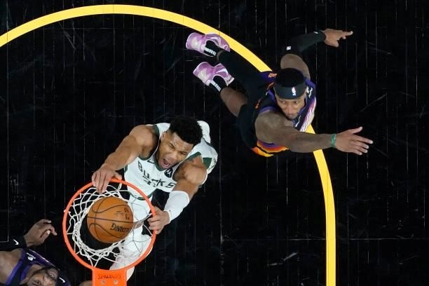 Milwaukee Bucks forward Giannis Antetokounmpo dunks as Phoenix Suns forward Torrey Craig, right, looks on during the first half in Game One of the...
