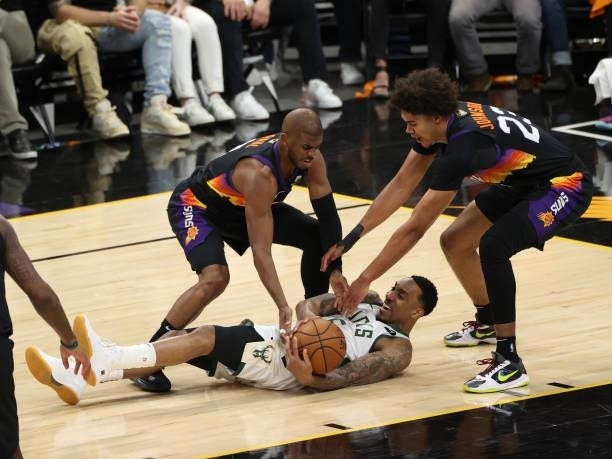 Chris Paul, Cameron Johnson of the Phoenix Suns and Jeff Teague of the Milwaukee Bucks fight for the ball during Game One of the 2021 NBA Finals on...