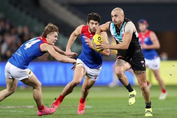 Sam Powell-Pepper of the Power heads toward goal with Christian Petracca of the Demons and Trent Rivers of the Demons during the 2021 AFL Round 17...