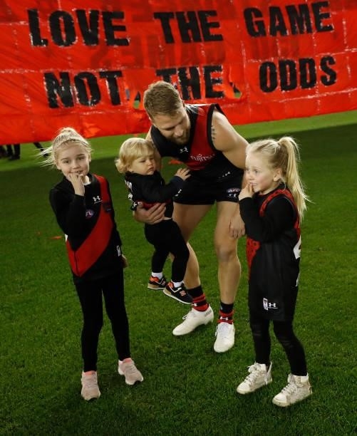 Jake Stringer of the Bombers runs through the banner with his children before his 150th match during the 2021 AFL Round 17 match between the Essendon...