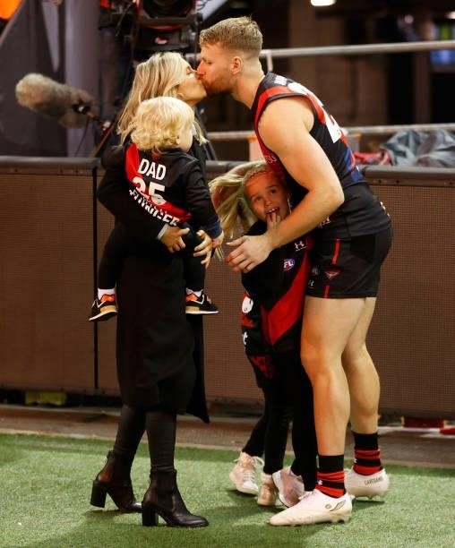 Jake Stringer of the Bombers kisses partner Taylor McVeigh as he runs onto the field with his children before his 150th match during the 2021 AFL...